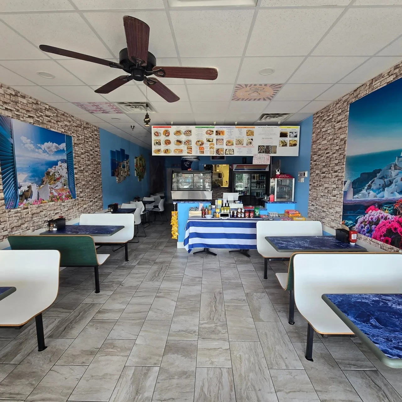 Taste of Greek’s Kingwood dining room with blue-and-white tables, Greek murals, and a Greek flag at the counter